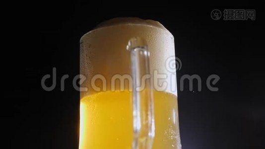 一杯带有泡沫的淡啤酒慢慢地在黑色背景上旋转。 特写镜头。视频