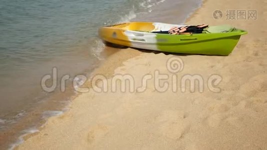 用桨划在沙滩上的皮艇，被蓝色的海水冲刷。 五颜六色的独木舟在波浪状的水晶水中，热带寂寞视频