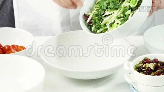 女人把新鲜的绿色沙拉拌在碗里。 一步一步地做蔬菜沙拉视频