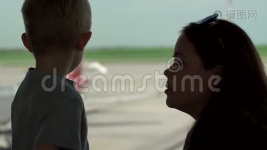 母亲的剪影和儿子站在机场的窗口。视频