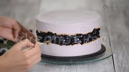 糖果师用金色糖浆装饰浆果蛋糕，手工制作。视频