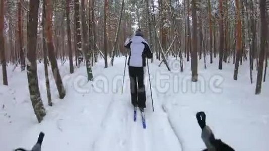 无法辨认的滑雪者在森林里行走。 第一人称观点视频