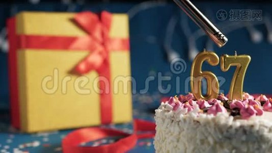 白色生日蛋糕数字67金蜡烛由打火机燃烧，蓝色背景灯和礼品黄色盒子与红色捆绑视频