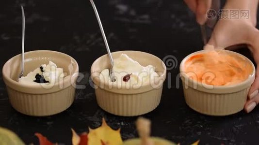 女性的手把奶油和凝胶状的食用色素混合在一个小碗里。视频