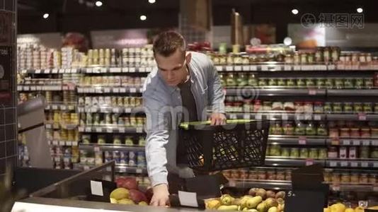 一家杂货店超市的农产品部门，年轻、积极的男人在买水果和蔬菜的画像视频