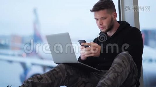 男子坐在机场，使用智能手机和笔记本电脑，飞机背景视频