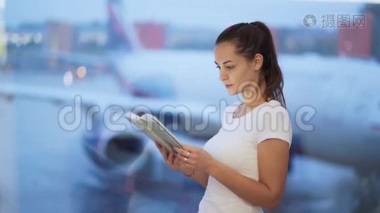 年轻女子在机场的窗户附近看书，背景模糊的飞机视频