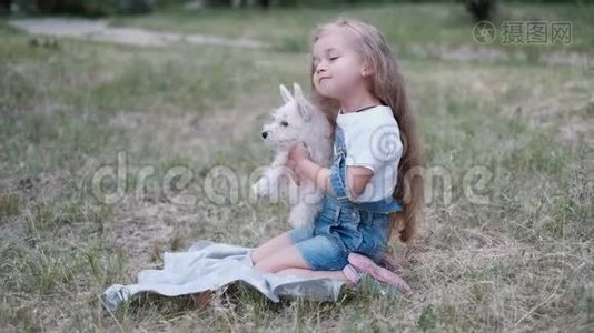 小金发女孩抱着西高地白梗小狗在公园。视频