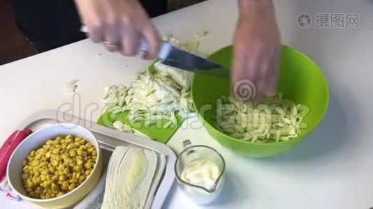 一个人做一份北京卷心菜沙拉。 用刀子把卷心菜切成切割板，然后扔进容器里。 在旁边视频