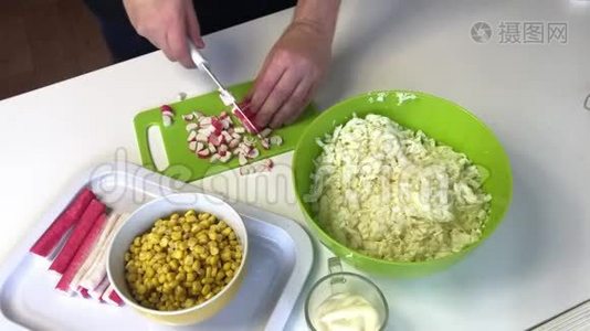 男人做沙拉。 将蟹片粘在砧板上，并加入一个容器与切碎的北京卷心菜。 其他的视频