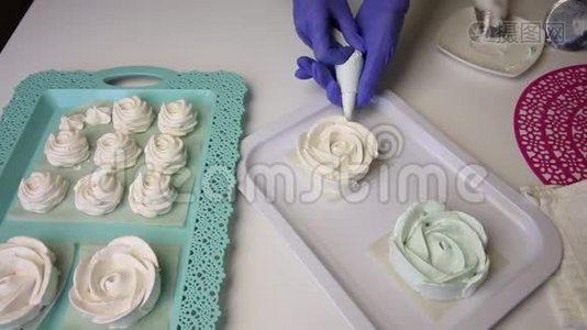 呈玫瑰状的棉花糖，在托盘上形成经典形状.. 一个女人用糕点包和喷嘴视频