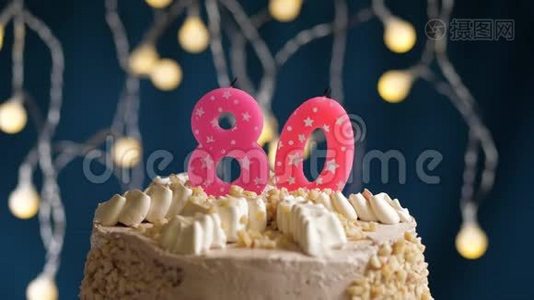 生日蛋糕，80个数字燃烧由较轻的粉红色蜡烛在蓝色的背景。 蜡烛被点燃了。 慢动作视频