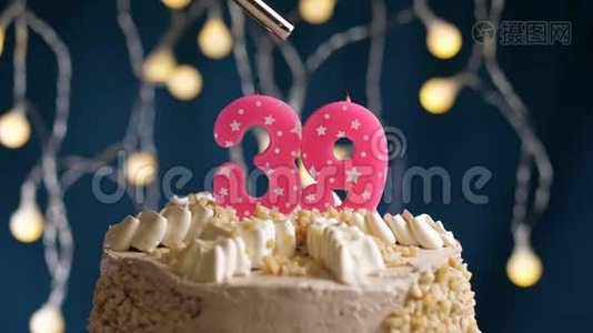 生日蛋糕，39个数字燃烧由较轻的粉红色蜡烛在蓝色的背景。 蜡烛被点燃了。 慢动作视频