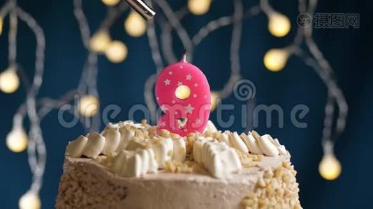 生日蛋糕，9个数字燃烧由较轻的粉红色蜡烛在蓝色的背景。 蜡烛被点燃了。 慢动作视频