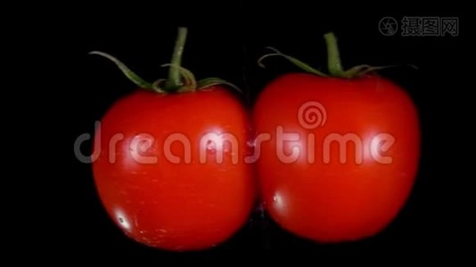两个成熟的红西红柿在黑色的背景上飞舞，碰撞着视频