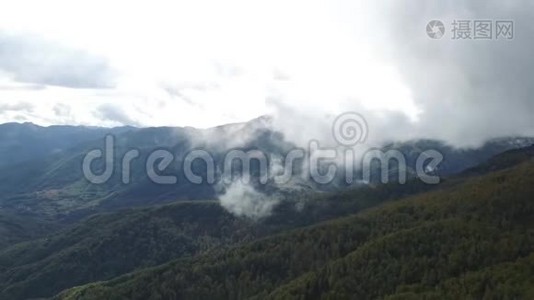 空中飞行在高山上的森林上空，穿过云层视频