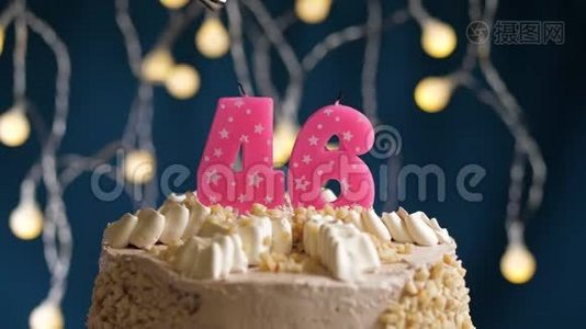生日蛋糕，46个数字燃烧由较轻的粉红色蜡烛在蓝色的背景上。 蜡烛被点燃了。 慢动作视频