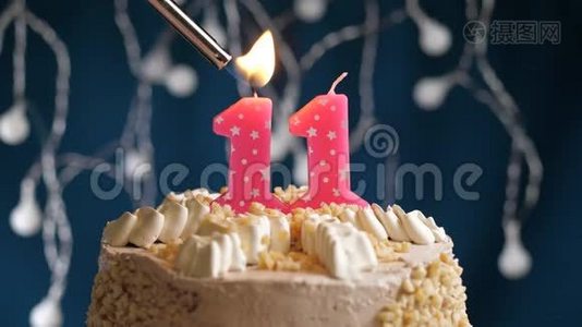 生日蛋糕，11个数字燃烧由较轻的粉红色蜡烛在蓝色的背景。 蜡烛被点燃了。 慢动作视频