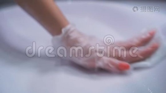 女人戴着手套`手洗白色浴室洗手池，每天消毒公共区域，以防止扩散视频