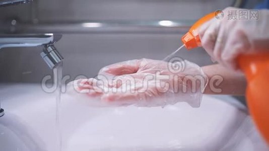 戴手套的女人清洗浴室的水龙头和水槽，在抹布上喷洒泡沫，每天清洗和消毒视频
