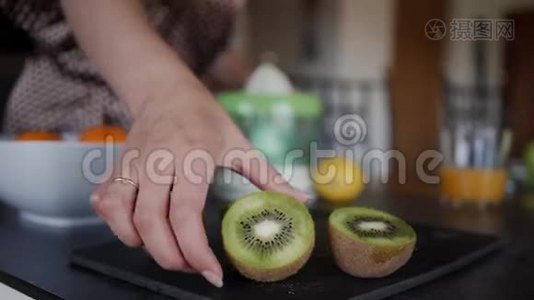 女孩从桌子上拿猕猴桃来榨果汁。 模糊的视频
