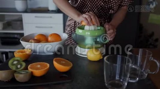 女人用电动榨汁机准备新鲜橙汁。 关门视频