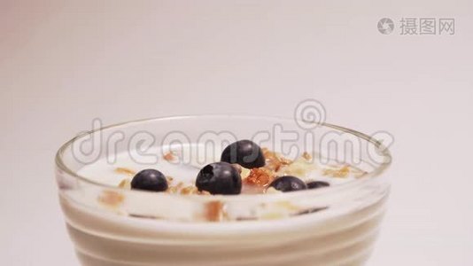 蓝莓倒在纯素酸奶透明玻璃，健康早餐。 在牛奶中加入浆果状的维生素视频