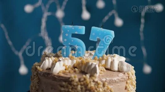 生日蛋糕，57号蜡烛在蓝色的背景上。 蜡烛吹灭了。 慢动作和特写视频