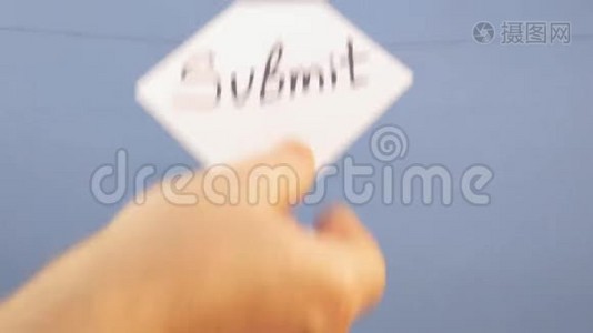 一个男人挂着一张白纸，上面写着黑色的铭文`在蓝色的背景上提交`视频