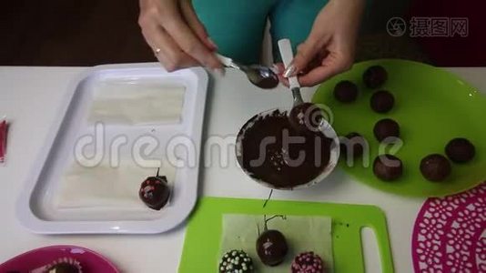 一个女人把一个巧克力海绵球放在表面。 装饰用洒水。 做一个土豆蛋糕。 盘子旁边是蛋糕视频