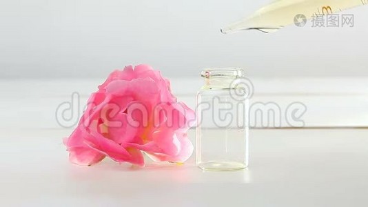 玫瑰花在白色背景上的精华在漂亮的玻璃瓶中视频