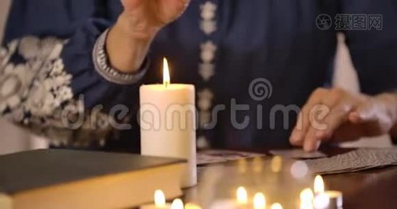 桌子上立着一支蜡烛的特写镜头，女性白种人的手模糊地在背景下拿出卡片视频