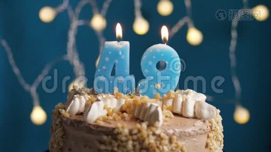 生日蛋糕，蓝色背景上有49支蜡烛。 蜡烛吹灭了。 慢动作和特写视频