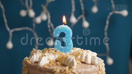 生日蛋糕，蓝色背景上有3支蜡烛。 蜡烛吹灭了。 慢动作和特写视频