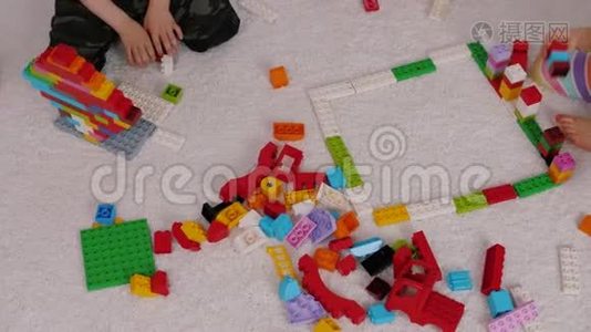 孩子们在幼儿园里坐在地毯上玩彩色塑料构造器视频