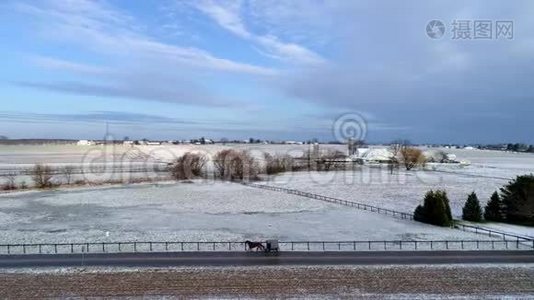 美丽乡村的空中景色，以及一匹马和一匹马在经过一场轻雪后沿着这条路行进视频