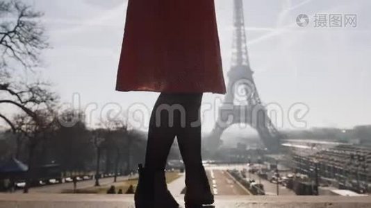 电影拍摄了美丽的白种人女士穿着红色的裙子摆姿势，在日出时旋转埃菲尔铁塔天景慢动作。视频