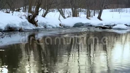 河中傍晚太阳的倒影.. 河的雪岸.. 流动的水经过融化的冰雪视频