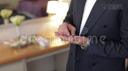 英俊的新郎手里拿着结婚戒指。 结婚的早晨。 商人视频