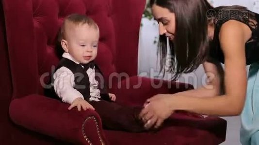 快乐的妈妈和心爱的小儿子在家玩，坐在柔软的椅子上。视频