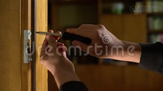 木匠修理门锁。 安装门把手.. 汉德曼拧紧门铰链。 修理工的手和一个视频