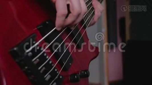 一个人弹红色电低音吉他的手指特写。视频