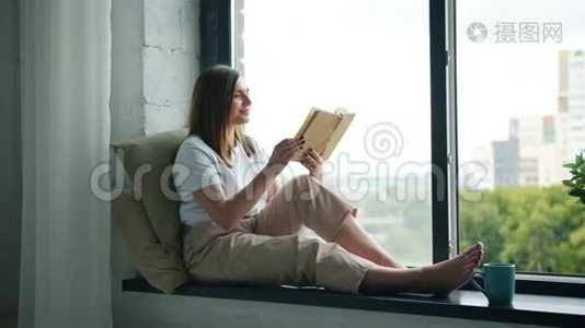 漂亮的女孩在家坐在窗台上翻书视频