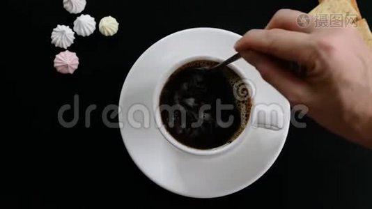 在杯中用手搅拌咖啡在黑色背景下，俯视视频