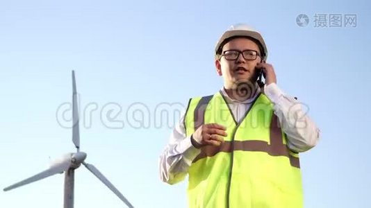 戴着眼镜、戴着安全帽、穿着明亮背心的亚洲工程师正在积极讨论如何在手机和视频