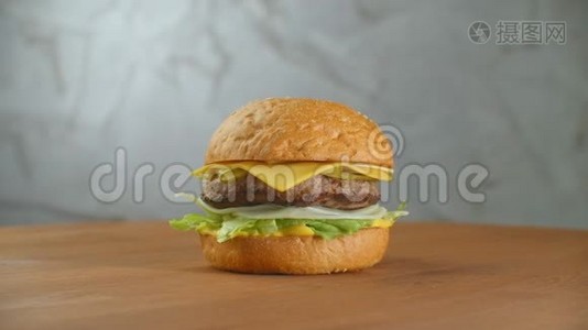 一个汉堡包在一块板上，炸薯条散落一地。特写美味的新鲜自制汉堡配生菜、奶酪视频