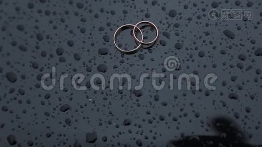 美丽的金色结婚戒指在潮湿的表面与水滴。视频