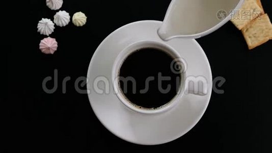将牛奶加入咖啡中，在黑桌上的杯子中搅拌咖啡视频
