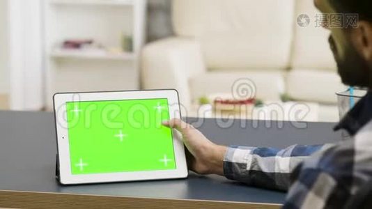 男子轻拍平板电脑的肩膀，上面有绿色屏幕视频