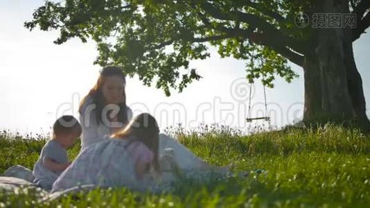 漂亮的妈妈和她的两个小宝贝一起野餐。视频